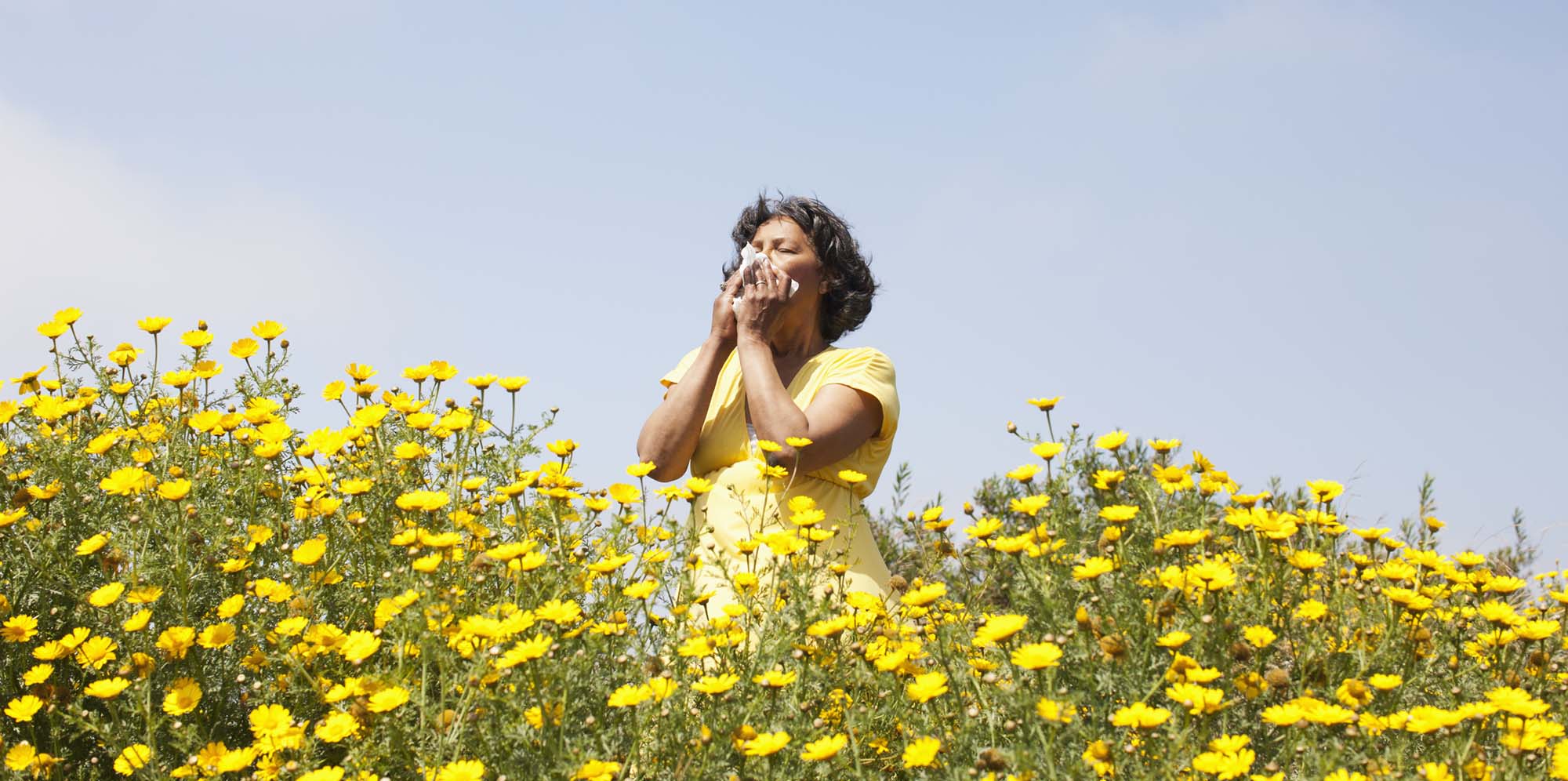 Woman blowing her nose surrounded by flowers